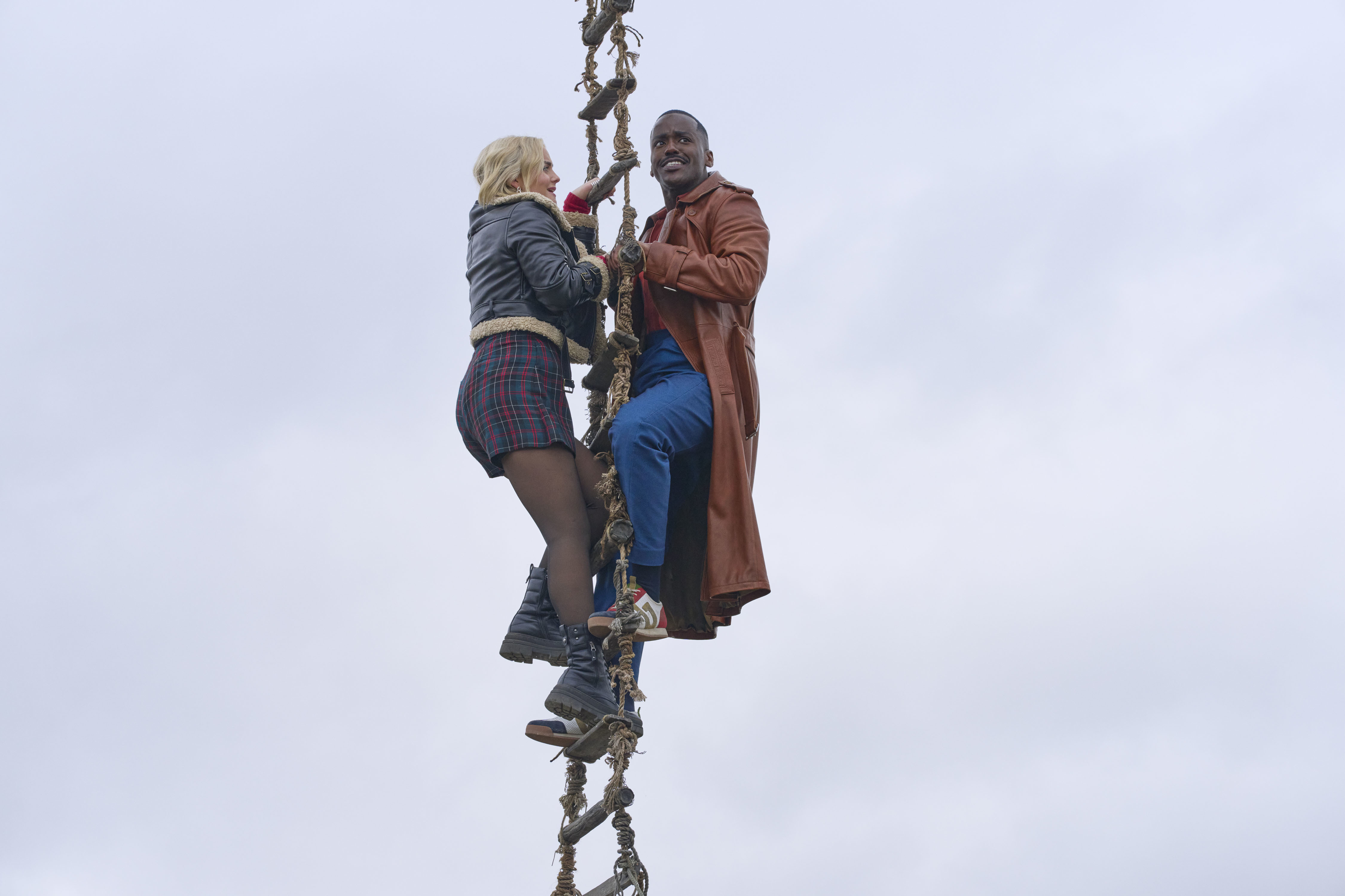 The Doctor and Ruby hold onto the rope ladder.