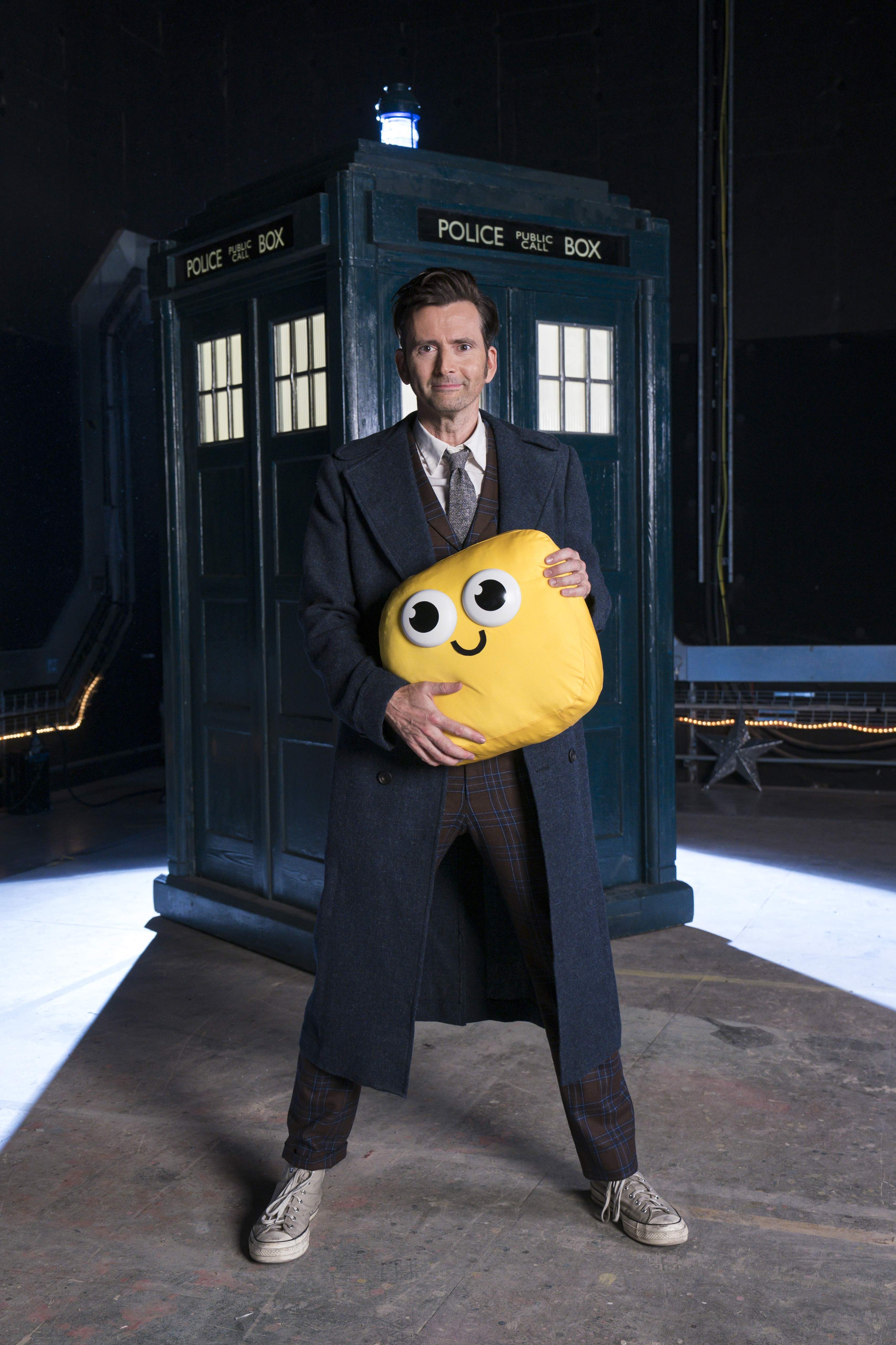 The Doctor stands in front of his TARDIS, holding a Bugbie.