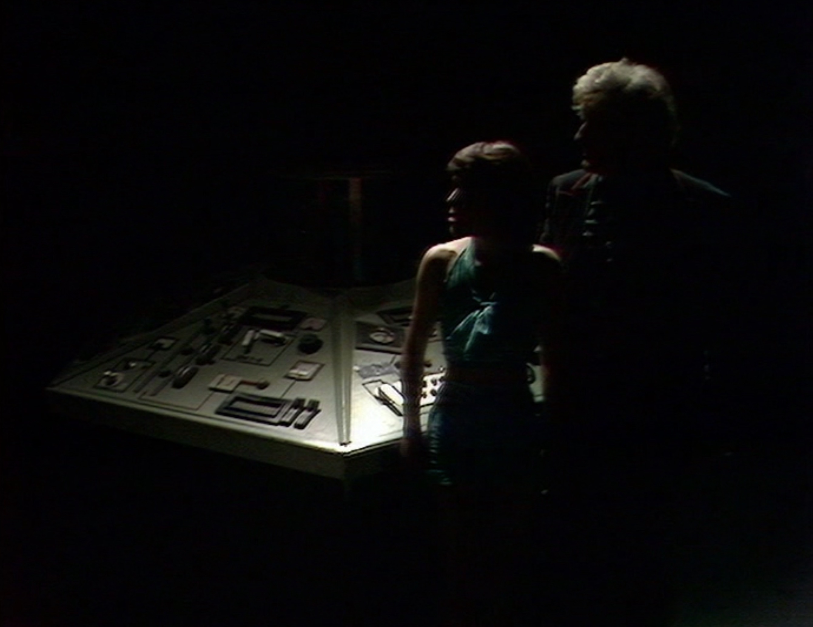 The Doctor and Sarah stand in the gloom of a powered down TARDIS. (TV: Death to the Daleks [+]Loading...["Death to the Daleks (TV story)"])