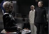 Davros, with Nyder, prepares to demonstrate his creations to the Kaled Scientific Elite.