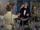 The Doctor introduces himself to Liz, who accepts his offered handshake.