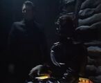 Davros is first seen, in shadow, flanked by Gharman.