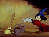 Mickey gestures towards the broom.