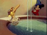 Mickey watches as the broom collects water.