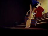 Mickey walks up the stairs with the broom.