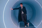 The Doctor crosses his legs in a tunnel in the TARDIS.