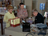 Liz Shaw and the Third Doctor attempt to establish the frequency of the "brain" within the energy unit while the Brigadier looks on.