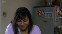 Rani Chandra in front of a postcard featuring Minnie Mouse, Mickey Mouse, Pluto, and Daisy Duck.