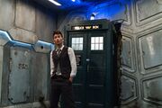 The Doctor stands next to the TARDIS, sonic screwdriver in the keyhole.